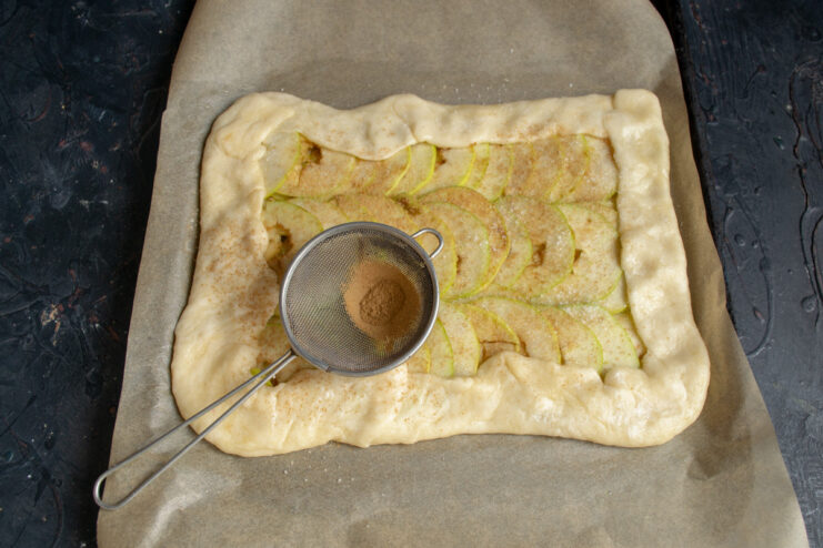 Final Touches: Adding Sugar and Cinnamon Before Baking A close-up of the galette being sprinkled with sugar and cinnamon.