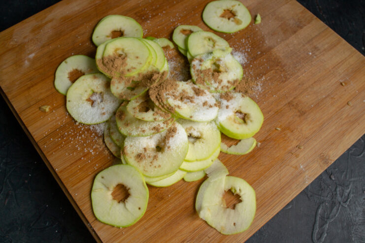 Seasoning Apple Slices with Lemon, Sugar, and Cinnamon Apple slices in a bowl being seasoned with lemon juice, sugar, and cinnamon.