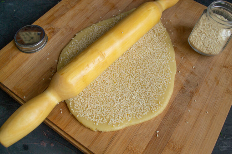 Sprinkling white sesame seeds generously over the rolled-out cookie dough.