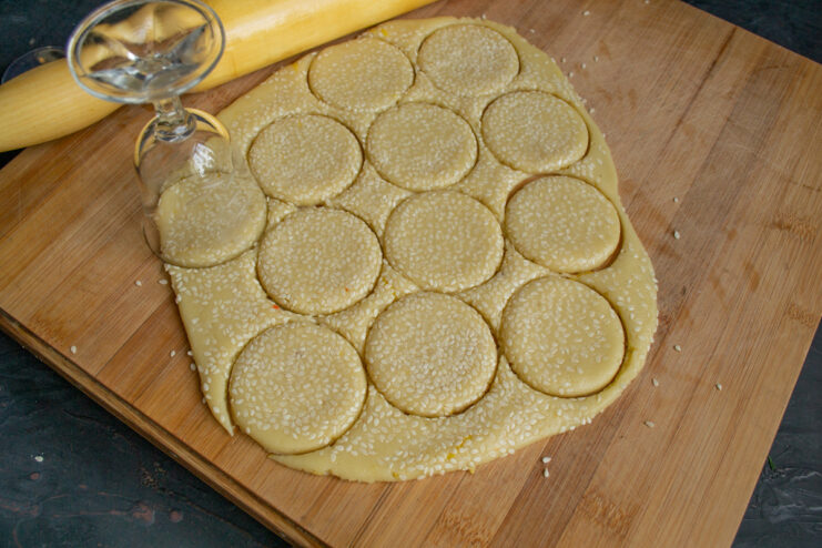 Using a round cookie cutter to cut shapes from the sesame-topped dough.
