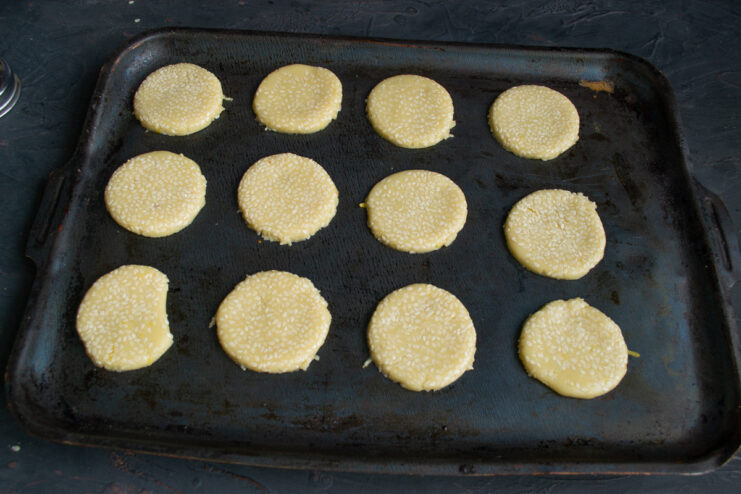 Placing the raw, cut-out cookies onto a parchment-lined baking sheet.