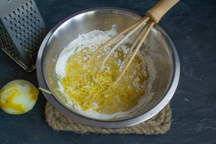 Grating fresh lemon zest on a fine grater directly into the dough mixture.