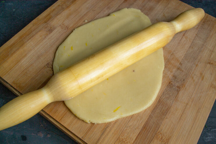 Chilled cookie dough placed on a wooden cutting board, ready for rolling.