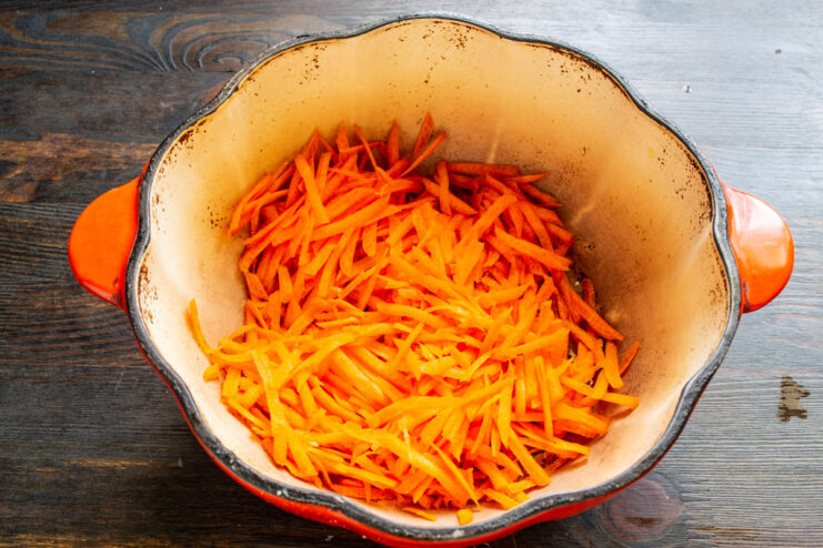 Grating Carrots for the Ragout Base Fresh carrots being grated on a coarse box grater.