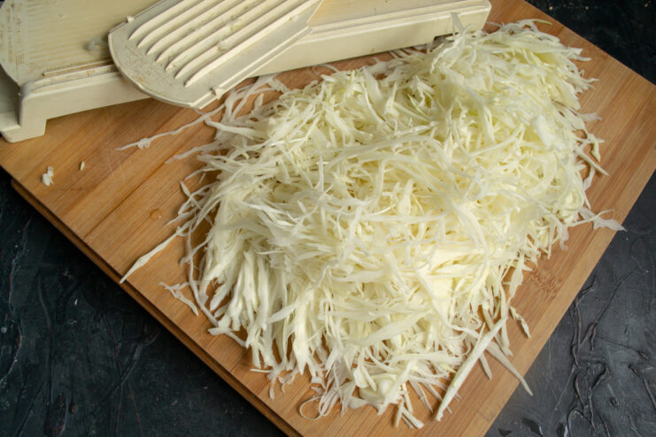 How to Finely Shred Cabbage for Tender Patties A pile of finely shredded white cabbage on a cutting board.