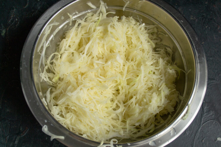 Massaging Cabbage with Salt to Soften It Hands massaging shredded cabbage with salt in a bowl to release moisture.