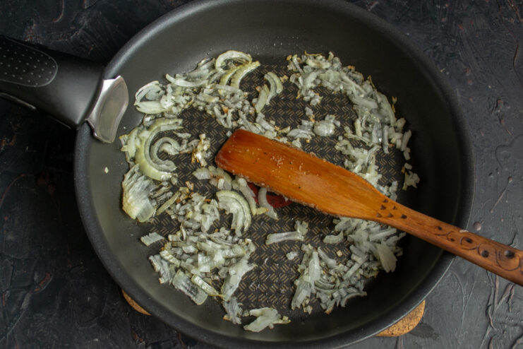 Sautéing Onions for the Tomato Sauce Base Finely chopped onions being sautéed in a pan until soft and translucent.