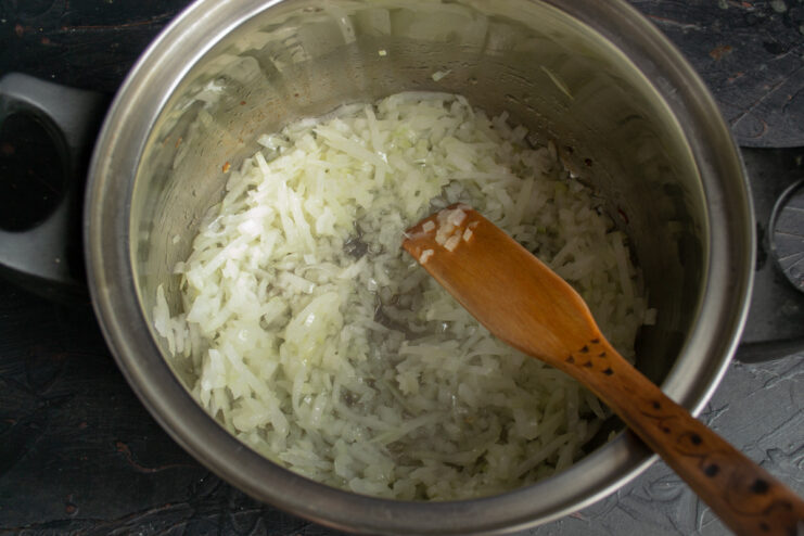 Sautéing Onions to Build the Flavor Base Chopped onions being sautéed in a pot until they become soft and translucent.