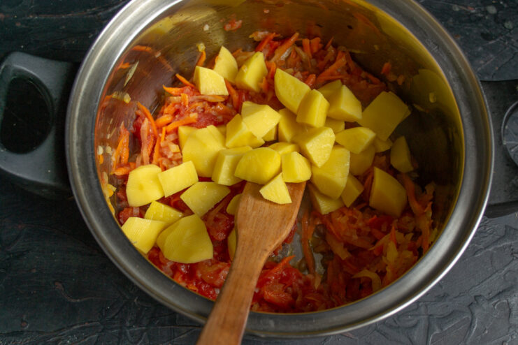 Adding Diced Potatoes for a Hearty Texture Diced raw potatoes being added to the pot with other vegetables for the soup.
