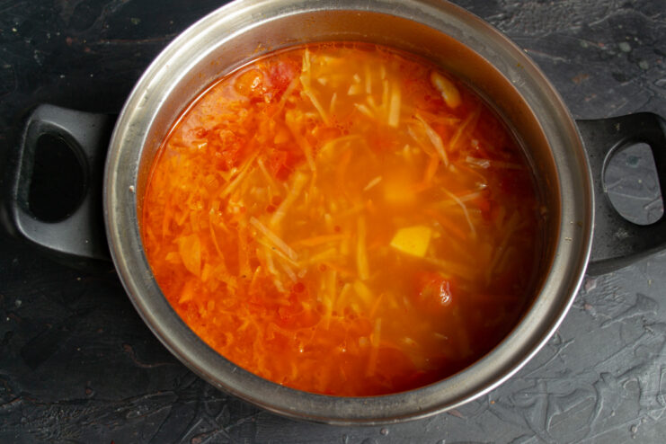 Simmering the Borscht to Perfection A pot of borscht simmering on the stove with the lid slightly ajar.