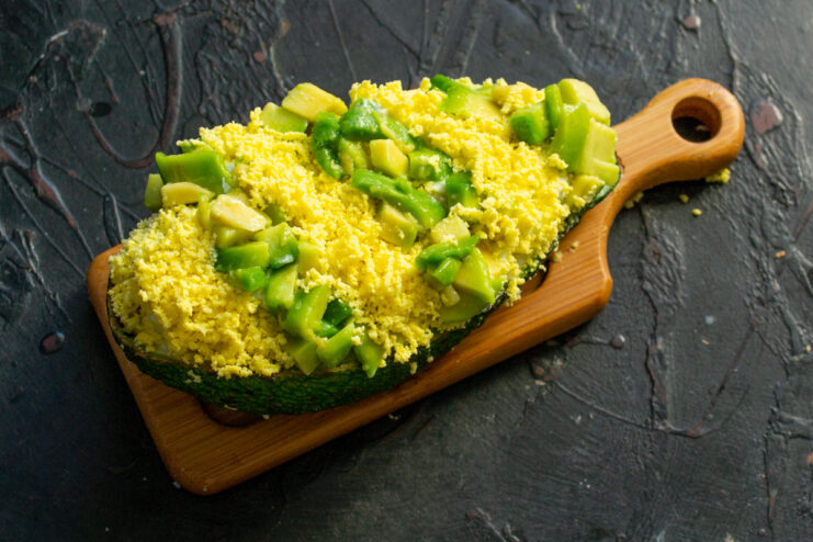 Garnishing Stuffed Avocado with Egg Yolk Garnishing a stuffed avocado half with a strip of bright yellow grated egg yolk.