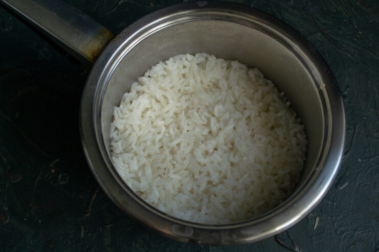 A pot with rice cooking on a stove, covered with a lid.