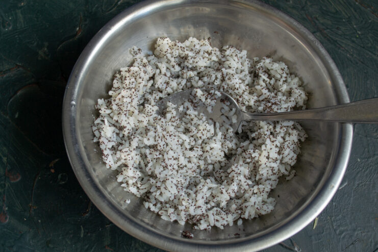 A bowl of sticky rice mixture being stirred with a spoon.