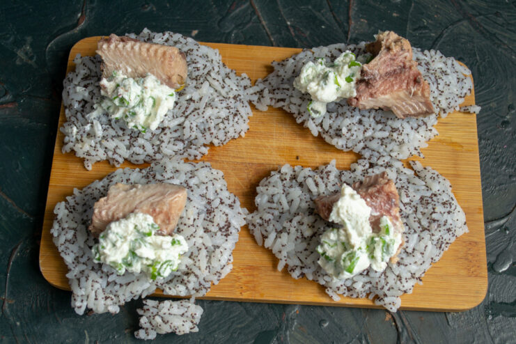 A spoonful of cream cheese and green onion mixture being added to the rice patty.