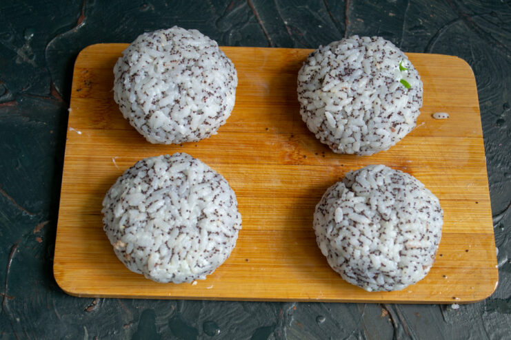 Hands shaping a rice patty with filling into a neat ball.
