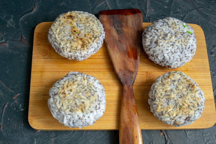 Stuffed rice balls being pan-fried in a skillet until golden brown.