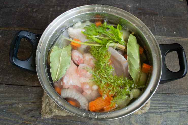 Step 1: Making the Flavorful Chicken Broth with Vegetables Chopped carrots and onions being added to a pot with pieces of raw chicken.