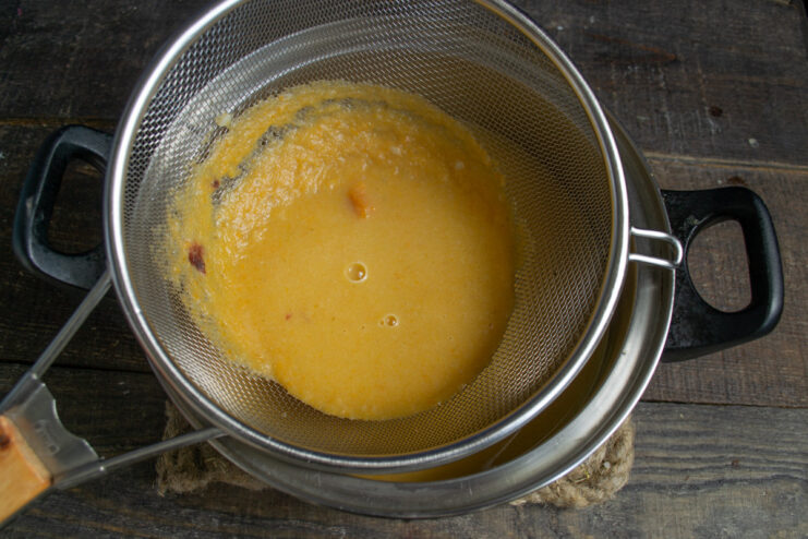 Straining the Blended Broth for a Silky Smooth Soup Base Straining the pureed vegetable broth into a pot with potatoes and grains.