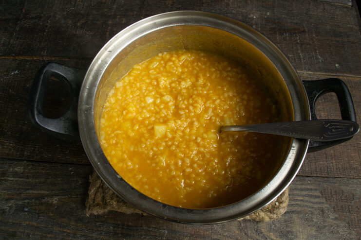 Final Simmer: Cooking the Grains and Potatoes to Perfection The finished soup simmering in a pot on the stove.