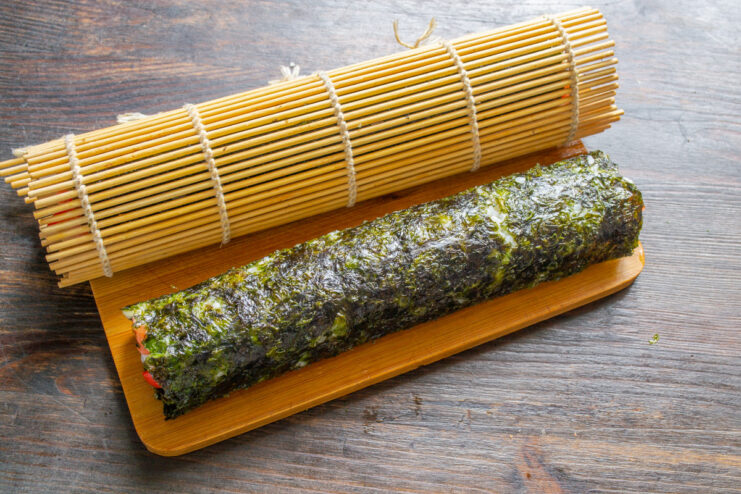 How to Roll Sushi with a Bamboo Mat Hands using a bamboo mat to tightly roll the nori sheet with fillings inside.