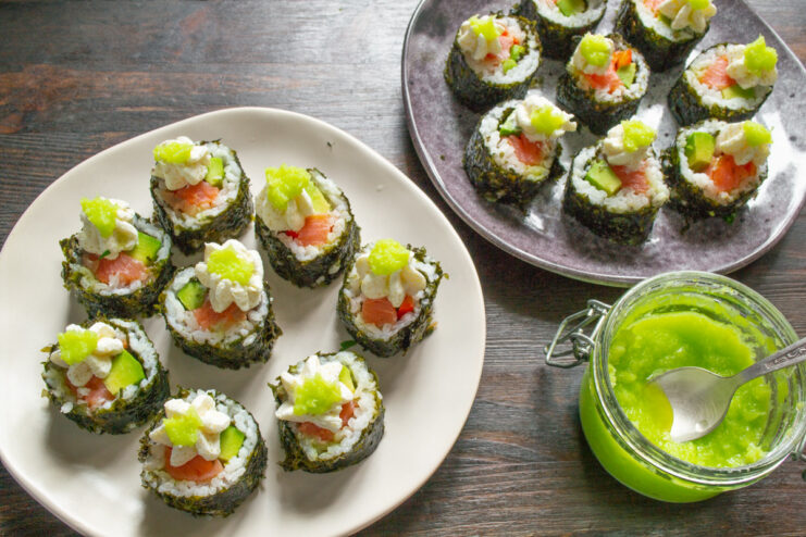 Garnishing the Finished Sushi Rolls Finished sushi rolls being garnished with a piped creamy cheese topping.