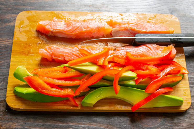 Prepping Bell Pepper for Rolls Red bell pepper being cut into thin, long strips for a sushi filling.