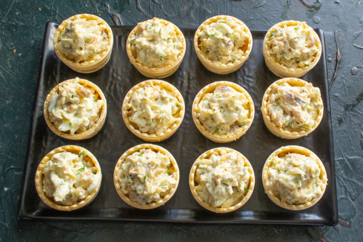 Filling Crispy Tartlet Shells with Salmon Salad Crispy tartlet shells being filled with the creamy salmon and anchovy salad.