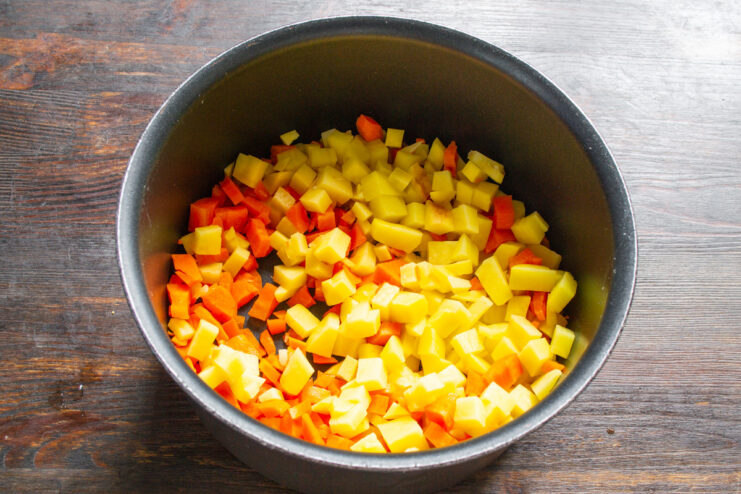 Step 1: Boiling the chopped potatoes and carrots for the salad. Chopped potatoes and carrots in a saucepan with boiling water being poured over them.