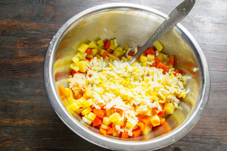 Step 5: Preparing the hard-boiled eggs for the salad. Hard-boiled eggs being grated on a coarse box grater into a bowl.