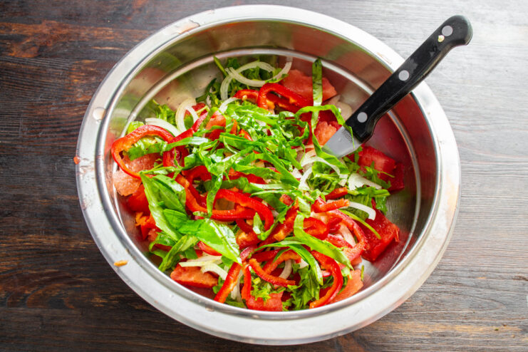 Chiffonade basil for elegant presentation and balanced flavor. A roll of basil leaves being sliced crosswise (chiffonade) on a cutting board.