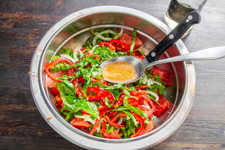 A splash of vinegar brightens up all the flavors in the salad. White wine vinegar being poured from a bottle into the salad bowl.
