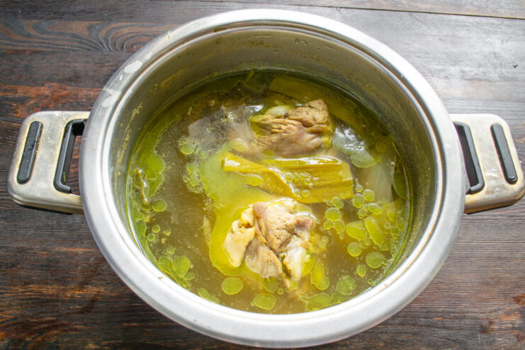 How to Boil Turkey for Salad Turkey drumsticks boiling in a pot with carrots, onions, and herbs to make broth.