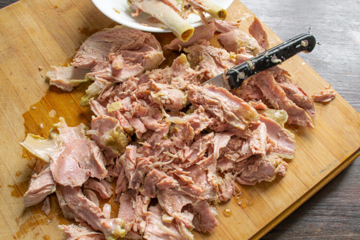 Preparing the Turkey Meat for the Salad Hands separating cooked turkey meat from the bones and skin.