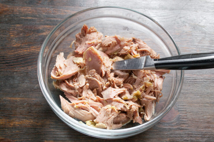 Shredding Cooked Turkey for a Rustic Texture A bowl of shredded cooked turkey meat, ready for the salad.