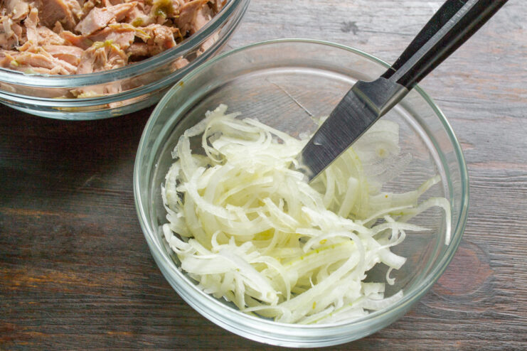 Slicing Sweet Onions for the Marinade Thinly sliced sweet onions on a cutting board.
