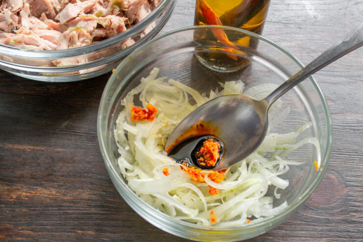 Making the Quick Pickle Marinade Apple cider vinegar and soy sauce being poured into the bowl with onions and adjika.