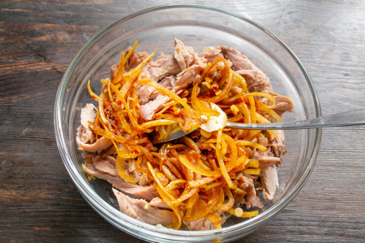 Combining Turkey with Pickled Onions Adding the bowl of marinated onions to the shredded turkey meat.