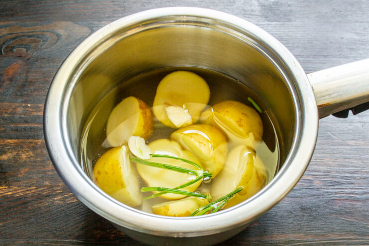 Cooking new potatoes until tender is the first step to a perfect salad. Small new potatoes boiling in a pot of water.