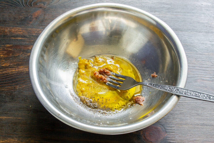 Whisking together the zesty dressing for the potato salad. Mixing the salad dressing ingredients in a bowl with a fork.