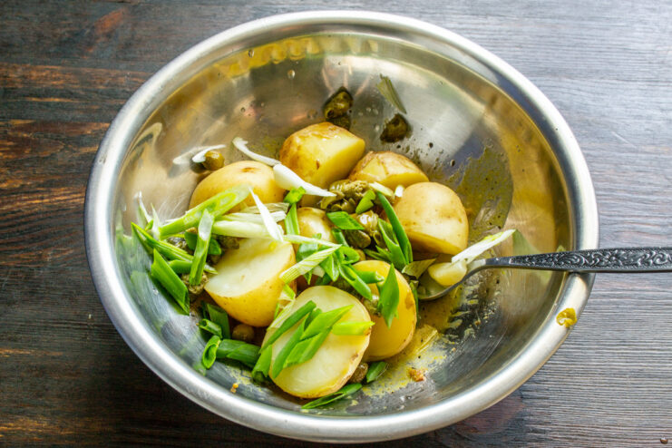 Freshly chopped green onions add a mild, crisp bite to the salad. Slicing green onions diagonally on a cutting board.