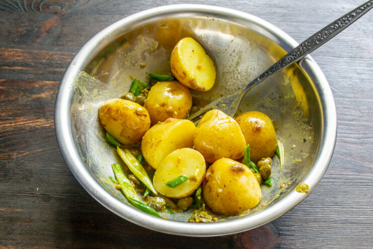 Giving the salad a final toss to combine all the delicious ingredients. Mixing the finished potato salad with all ingredients in a bowl.