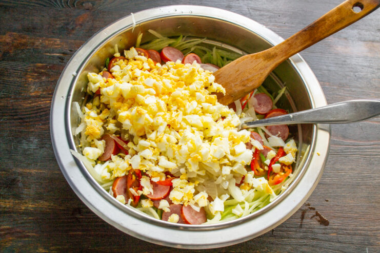 Adding chopped hard-boiled eggs to the salad Adding finely chopped hard-boiled eggs to the salad bowl.
