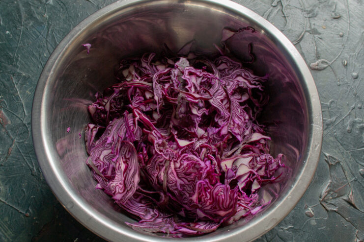 How to Thinly Shred Red Cabbage for the Perfect Salad Texture Close-up of red cabbage being thinly shredded on a cutting board.