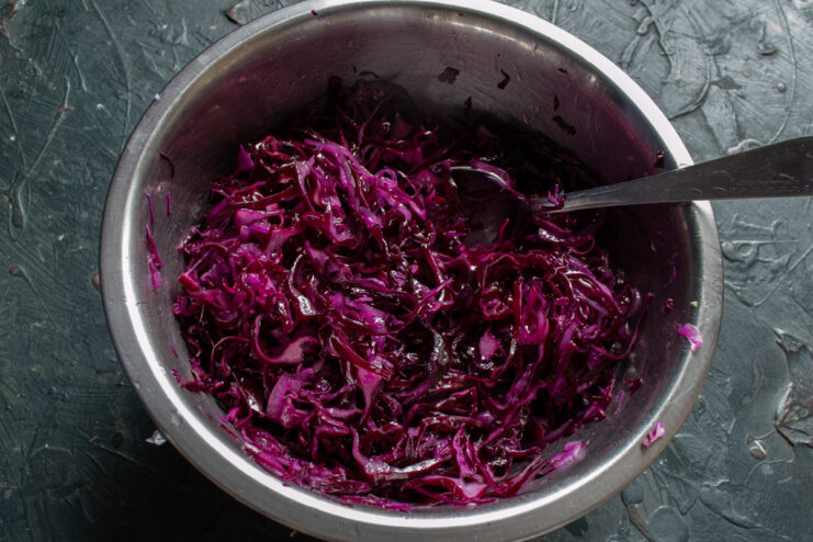 Dressing the Red Cabbage Salad with High-Quality Extra Virgin Olive Oil Pouring extra virgin olive oil into a bowl of seasoned red cabbage salad.