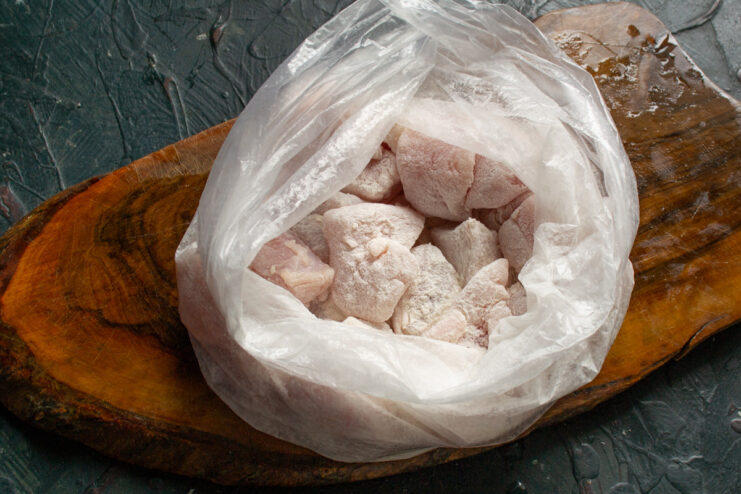 Coating Turkey Pieces in Cornstarch for a Crispy Texture Diced turkey pieces being placed into a plastic bag with cornstarch.