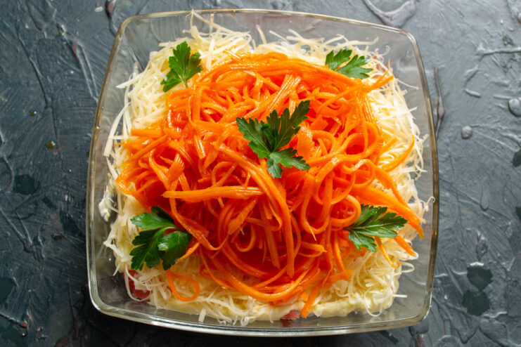 The final touch: garnishing the salad before serving. The finished Korean carrot and chicken salad, topped with carrots and garnished with parsley.
