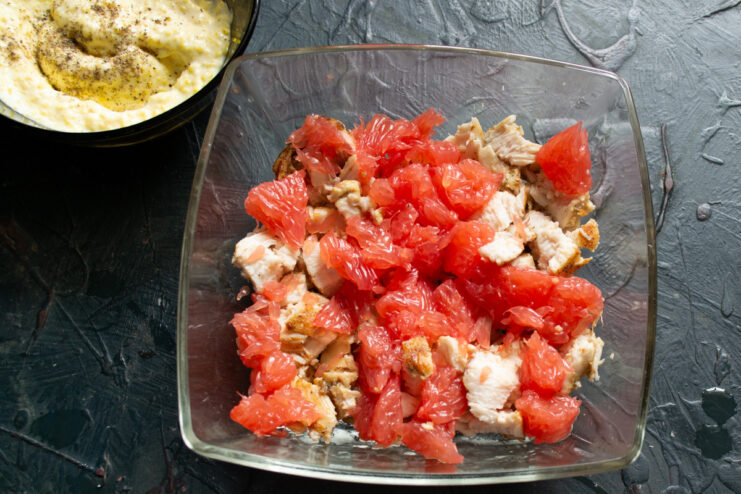 Layering juicy grapefruit over the diced chicken. Assembling the salad: a layer of diced chicken topped with fresh grapefruit segments.