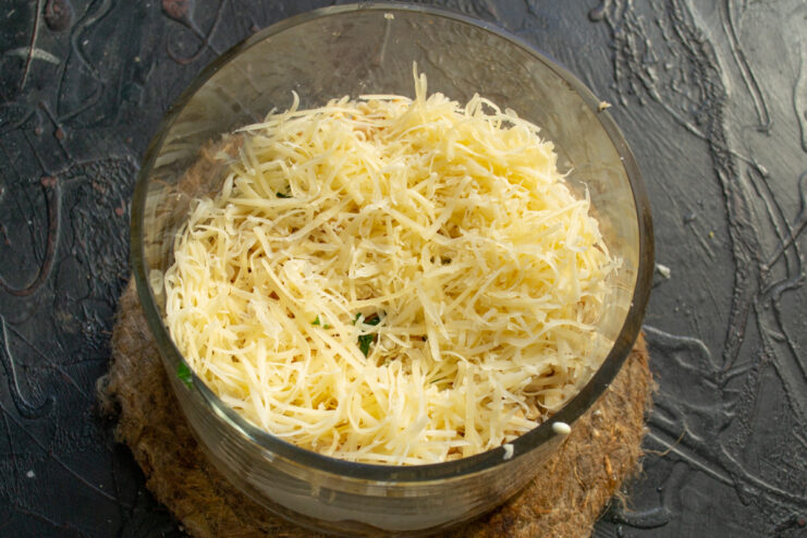 Grating cheese for a savory touch A block of semi-soft cheese being grated over the salad.