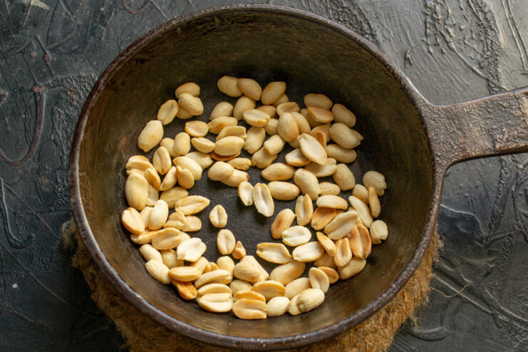 How to toast peanuts to bring out their nutty flavor Blanched peanuts being toasted in a black skillet.