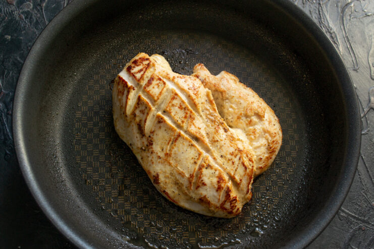 Searing the chicken to lock in juices and flavor Marinated chicken breast searing in a hot pan to get a golden crust.